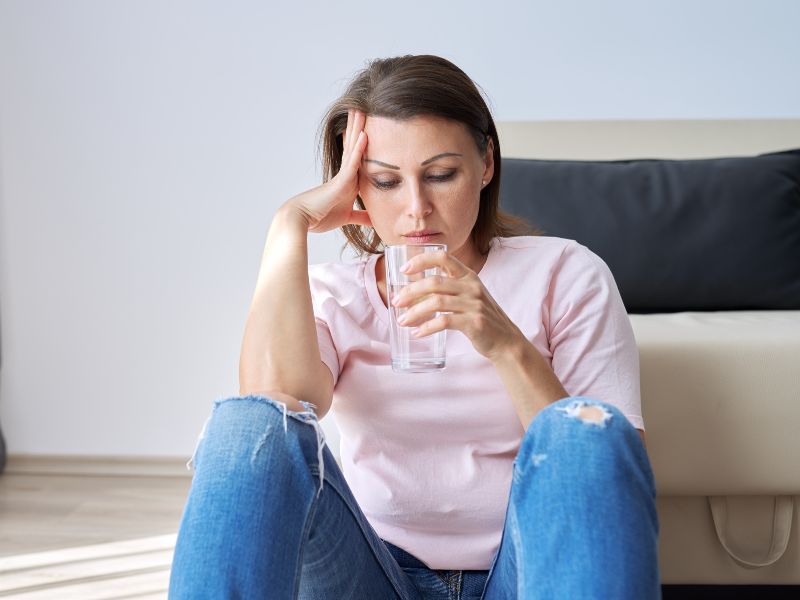 Mujer sentada en el suelo con vaso de agua